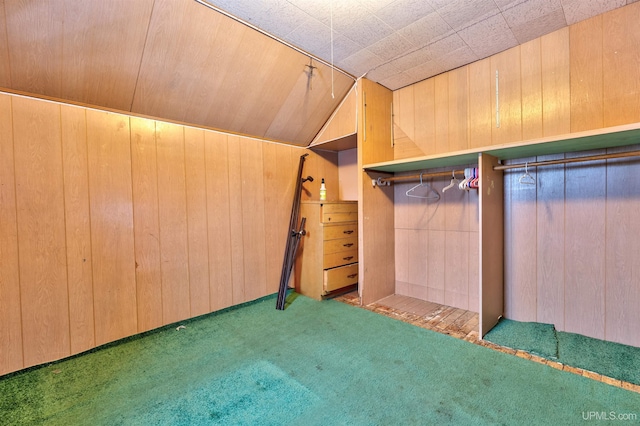 interior space with dark colored carpet, lofted ceiling, and wood walls