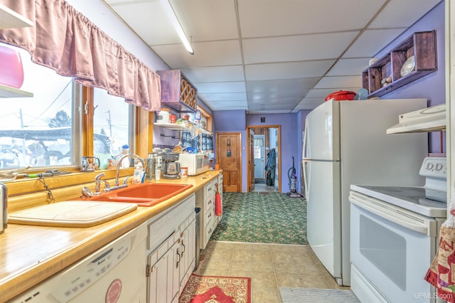 kitchen featuring sink, white cabinets, light carpet, a drop ceiling, and white appliances