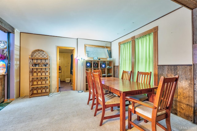 carpeted dining area featuring wooden walls and a healthy amount of sunlight