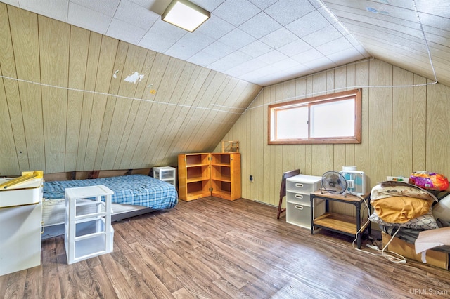 bedroom featuring vaulted ceiling, hardwood / wood-style floors, and wooden walls