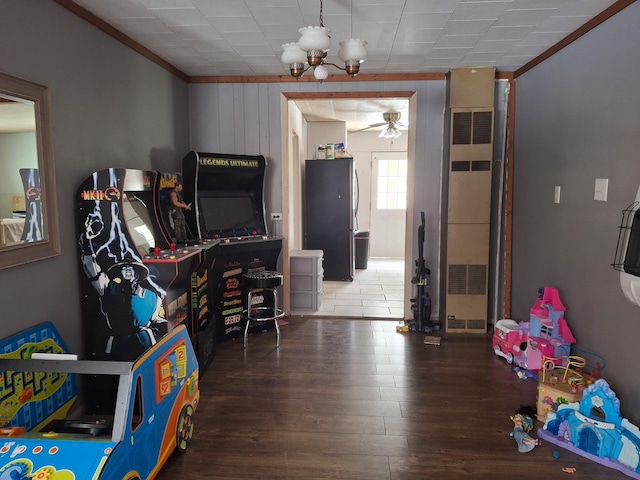 recreation room with dark hardwood / wood-style flooring, crown molding, and ceiling fan with notable chandelier