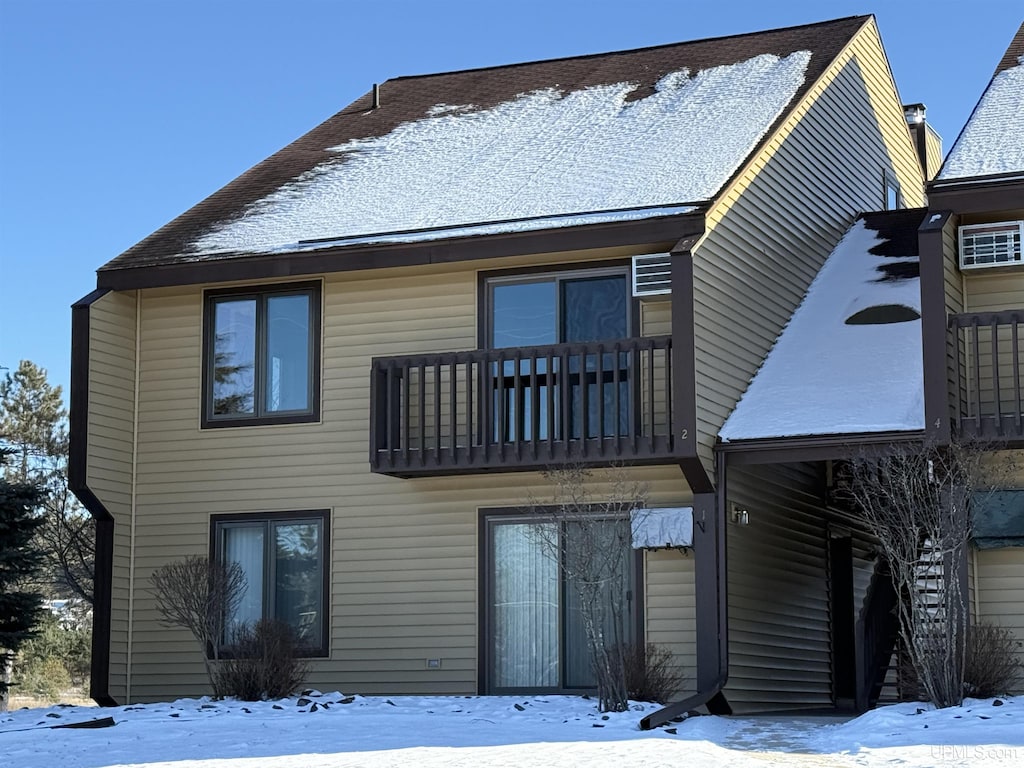 snow covered rear of property featuring a balcony