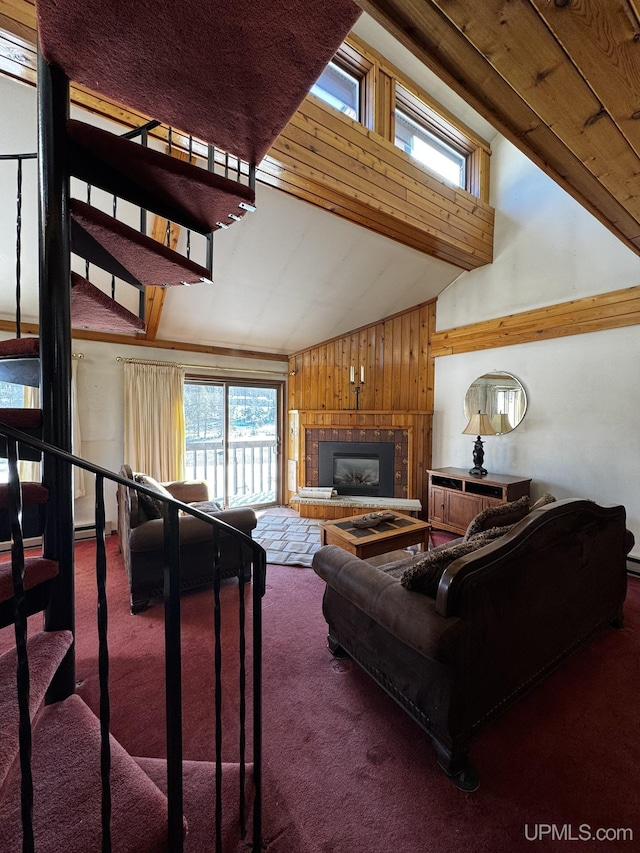 carpeted living room featuring high vaulted ceiling, a tile fireplace, and wood walls