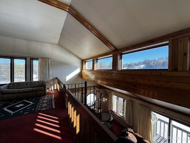 hall with lofted ceiling and dark colored carpet