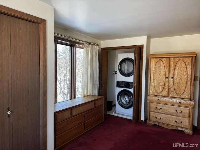 laundry area with stacked washer and clothes dryer and dark carpet