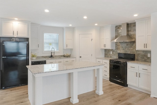 kitchen featuring a kitchen island, sink, white cabinets, black appliances, and wall chimney range hood