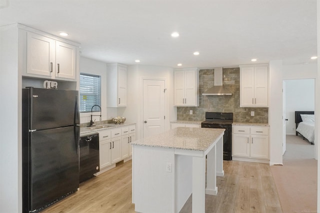 kitchen with white cabinetry, a kitchen island, wall chimney exhaust hood, and black appliances