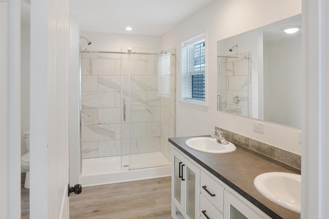 bathroom with wood-type flooring, toilet, vanity, and a tile shower