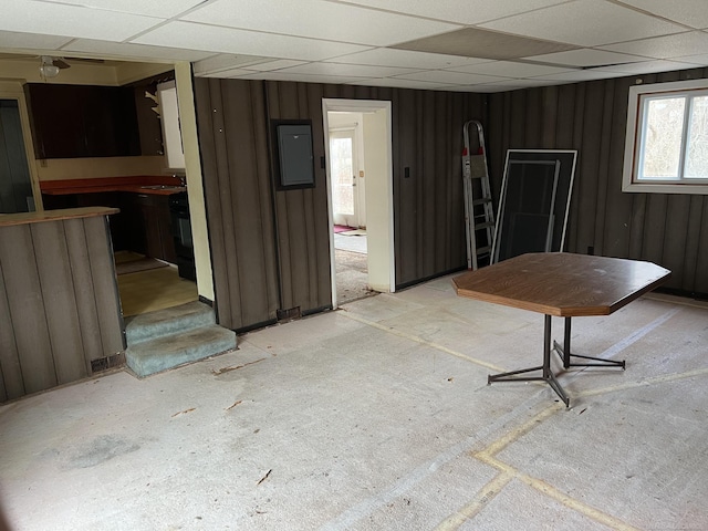 misc room featuring a paneled ceiling, electric panel, and wood walls