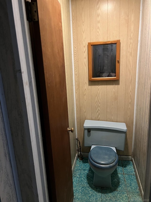 bathroom with wood walls and toilet