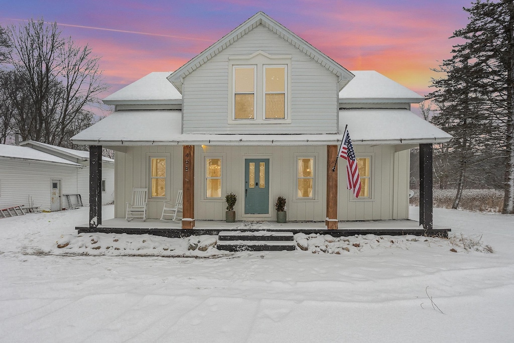 snow covered property with covered porch