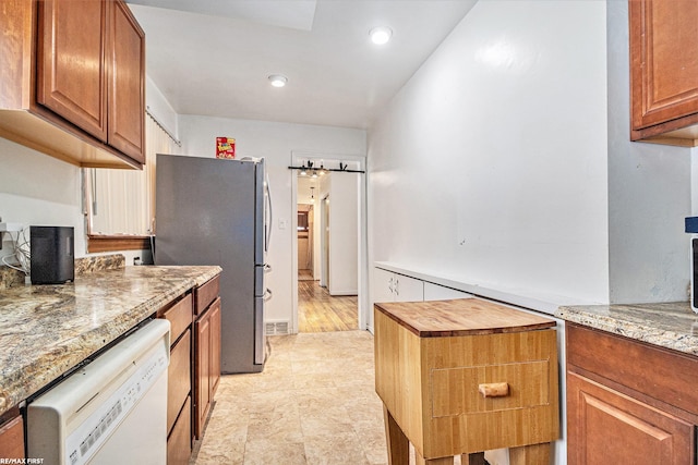 kitchen with stainless steel refrigerator, a barn door, dishwasher, and light stone countertops