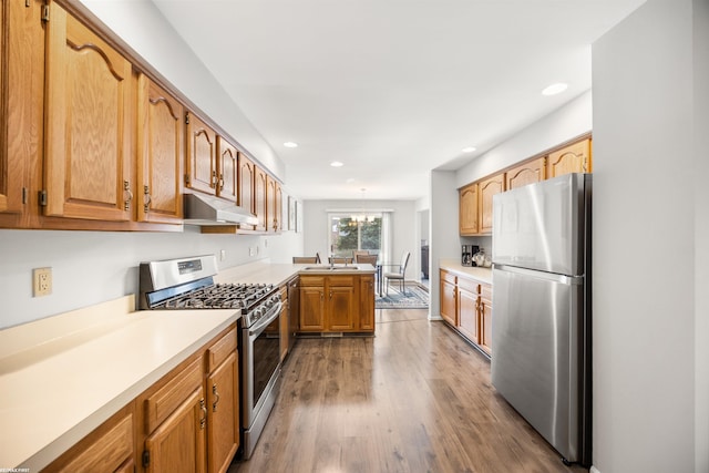 kitchen with wood-type flooring, sink, a chandelier, kitchen peninsula, and stainless steel appliances