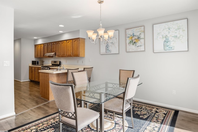 dining area with an inviting chandelier, dark hardwood / wood-style flooring, and sink