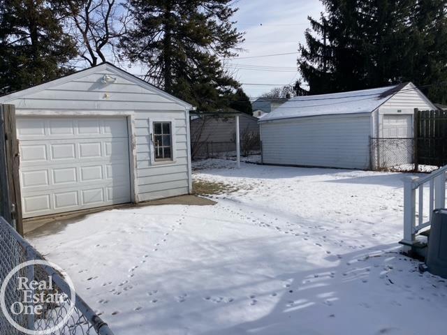 snow covered garage featuring a garage and fence