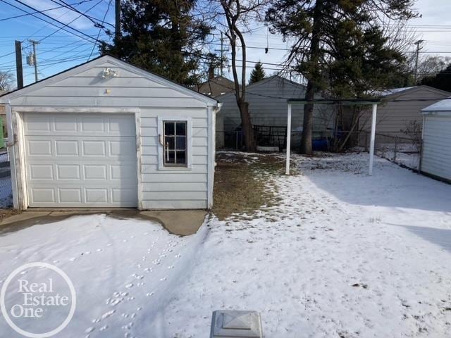 snow covered garage with a detached garage