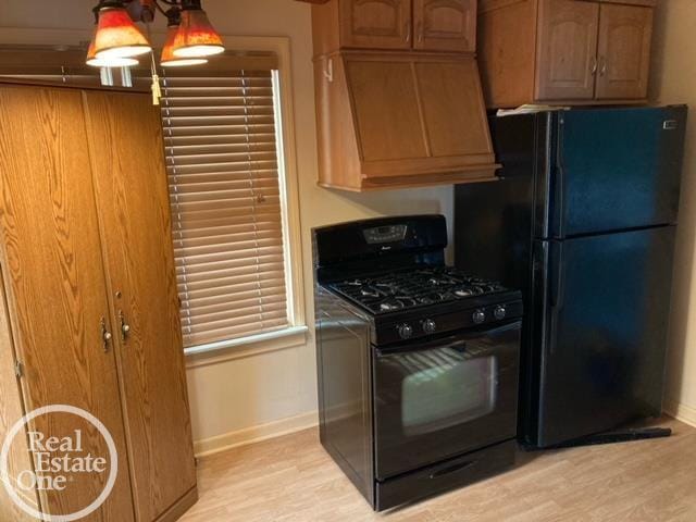 kitchen with premium range hood, baseboards, light wood-style flooring, and black appliances