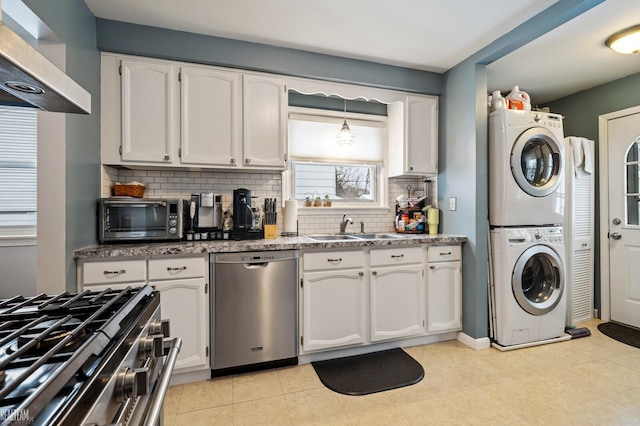 kitchen with white cabinetry, appliances with stainless steel finishes, stacked washer and clothes dryer, and sink