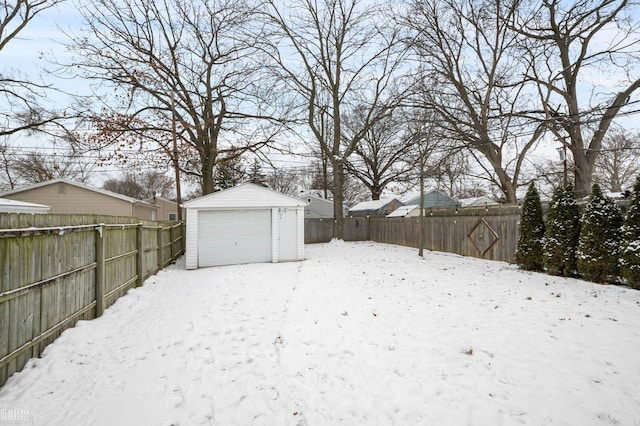 yard layered in snow featuring a garage and an outbuilding