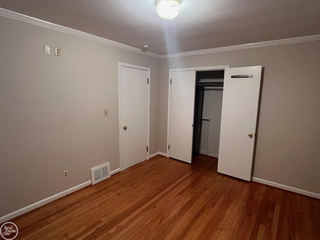 unfurnished bedroom with hardwood / wood-style flooring, ornamental molding, and a closet