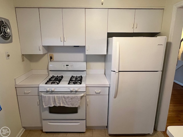 kitchen with white cabinetry, light tile patterned floors, and white appliances