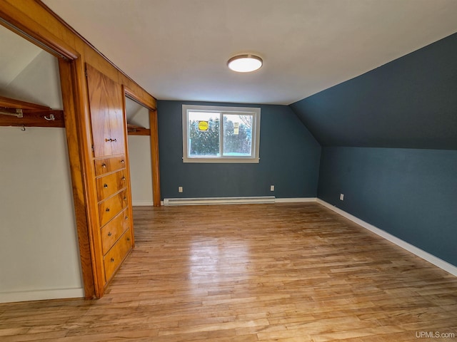 additional living space featuring baseboard heating, light hardwood / wood-style floors, and vaulted ceiling