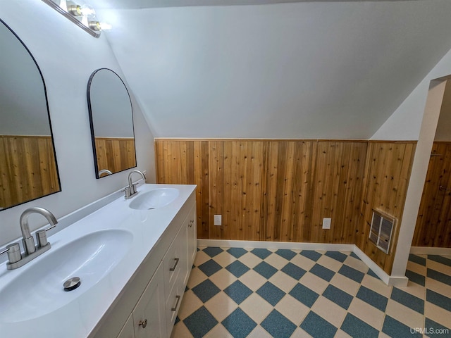 bathroom featuring vanity, vaulted ceiling, and wood walls