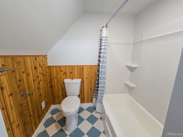 bathroom with toilet, shower / tub combo, and wood walls