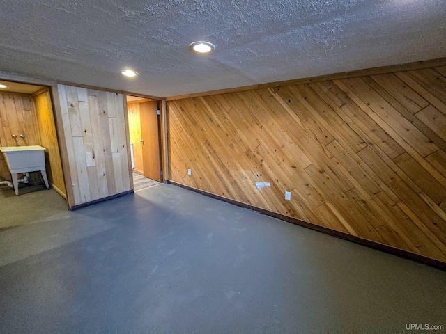 basement featuring a textured ceiling and wood walls