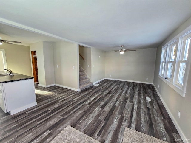 unfurnished living room with sink, dark wood-type flooring, and ceiling fan