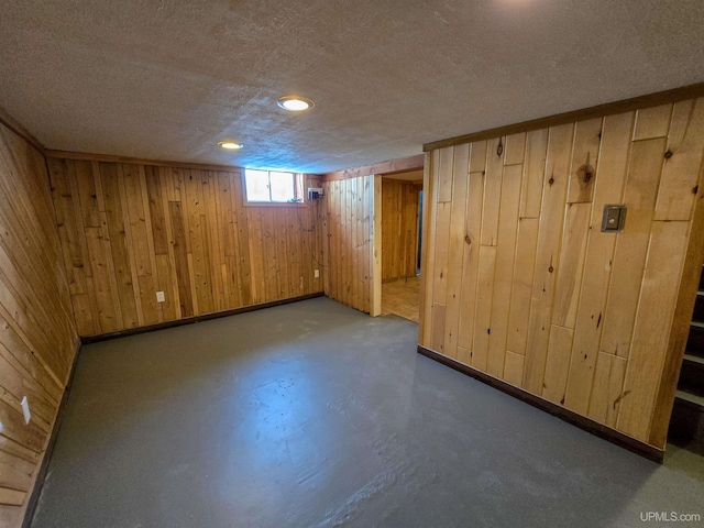 basement with wooden walls and a textured ceiling