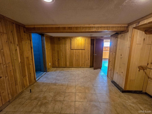 basement featuring wooden walls and a textured ceiling