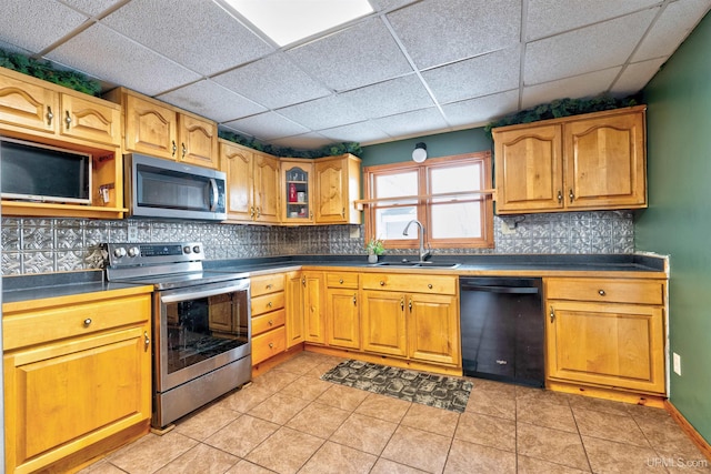 kitchen featuring sink, light tile patterned floors, appliances with stainless steel finishes, tasteful backsplash, and a drop ceiling