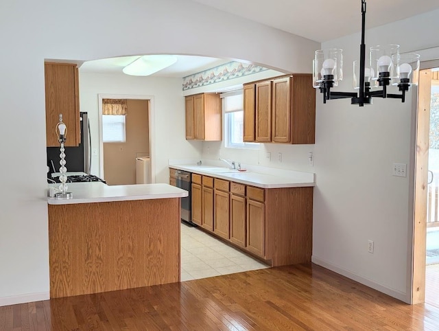 kitchen featuring sink, light hardwood / wood-style flooring, appliances with stainless steel finishes, kitchen peninsula, and washer / clothes dryer