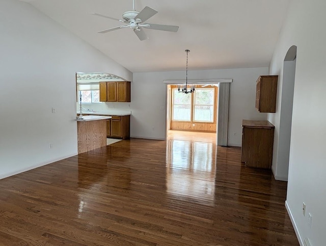 interior space featuring dark wood-type flooring, lofted ceiling, and ceiling fan with notable chandelier