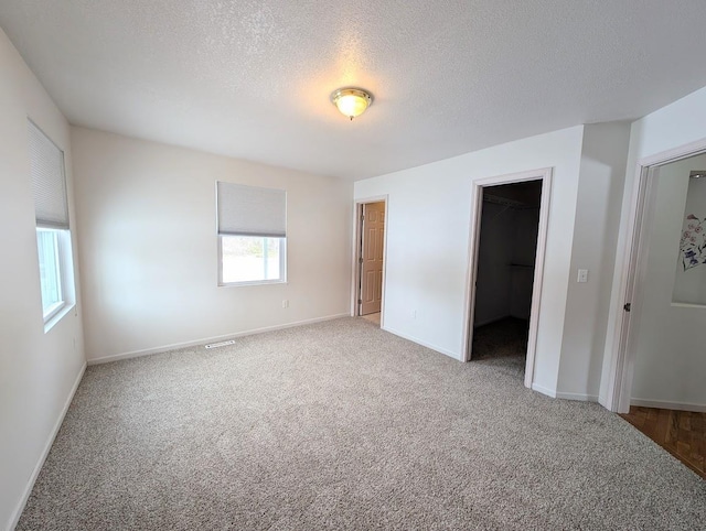 unfurnished bedroom featuring multiple windows, carpet floors, a spacious closet, and a closet