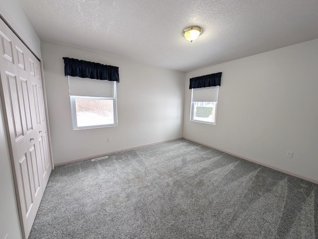 carpeted empty room with a textured ceiling