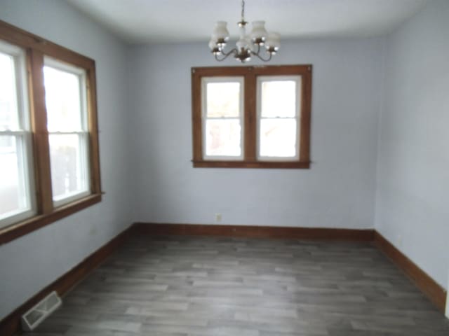 spare room featuring an inviting chandelier and wood-type flooring