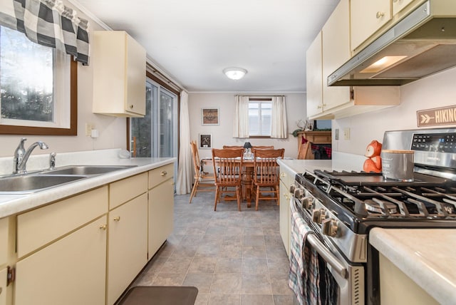 kitchen featuring stainless steel range with gas cooktop, sink, and cream cabinets