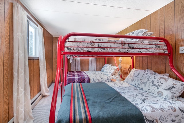 bedroom with baseboard heating, carpet, and wood walls