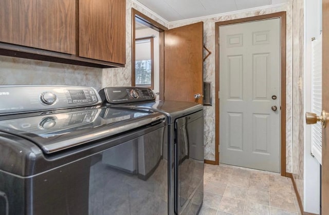 clothes washing area featuring crown molding, cabinets, and washer and clothes dryer