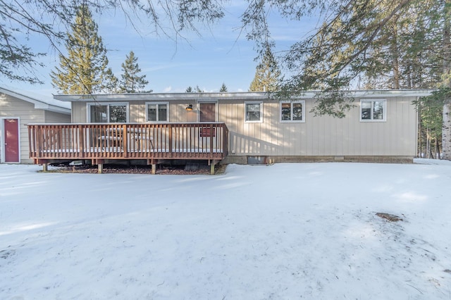 snow covered back of property featuring a wooden deck