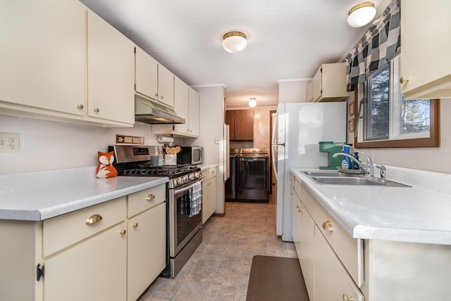 kitchen with cream cabinets, stainless steel appliances, sink, and washer and dryer