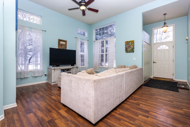 living room featuring dark wood-type flooring, ceiling fan, and a towering ceiling