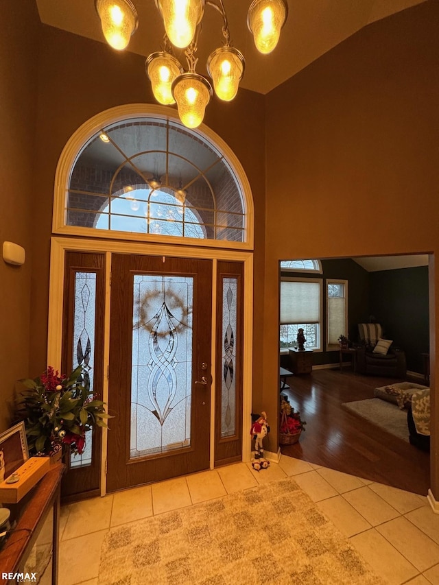 tiled entrance foyer with high vaulted ceiling and an inviting chandelier