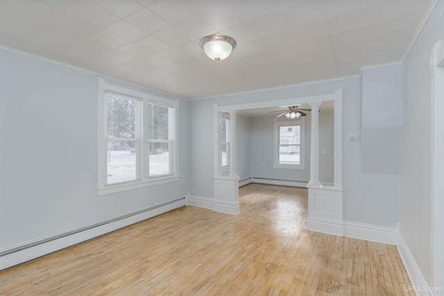 spare room with ornate columns, a baseboard heating unit, and light hardwood / wood-style flooring