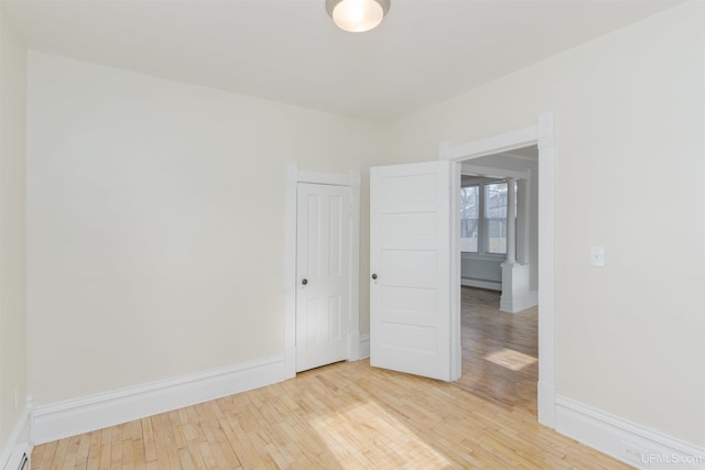 unfurnished room featuring a baseboard radiator and light wood-type flooring