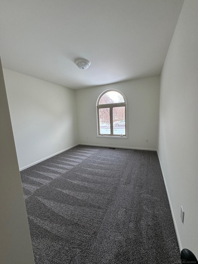 unfurnished room featuring dark carpet