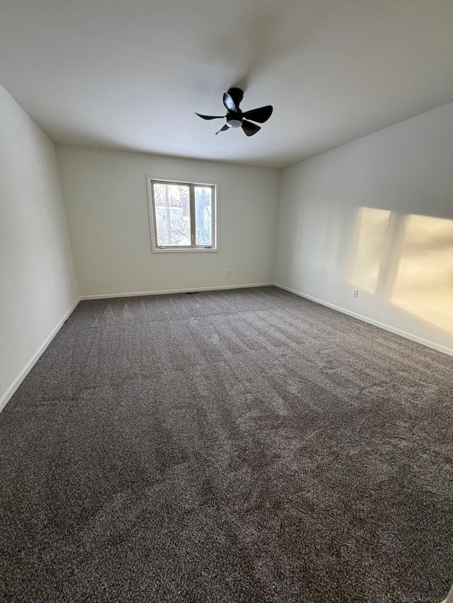 empty room featuring ceiling fan and dark colored carpet