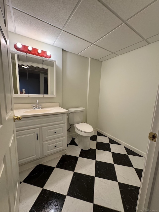 bathroom with vanity, toilet, and a drop ceiling